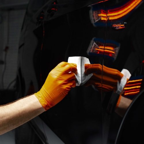 Car polish wax worker hands polishing car. Buffing and polishing vehicle with ceramic. Car detailing. Man holds a polisher in the hand and polishes the car with nano ceramic. Tools for polishing