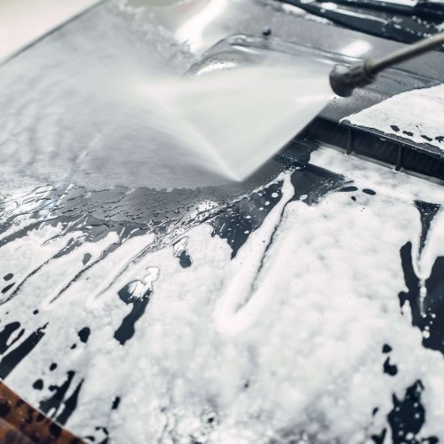 Carwash service, car cleaning, top view on hood. Auto detailing, washing foam off