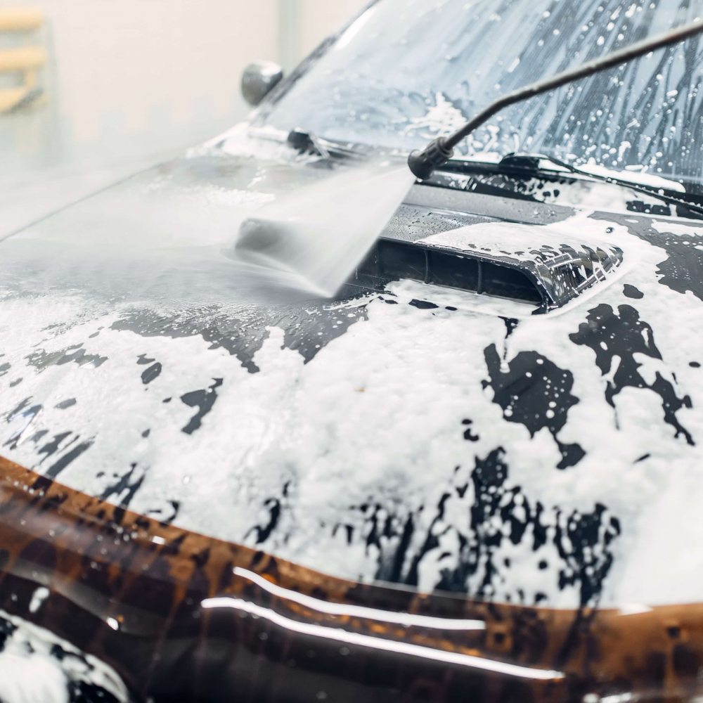 Carwash service, car cleaning, top view on hood. Auto detailing, washing foam off