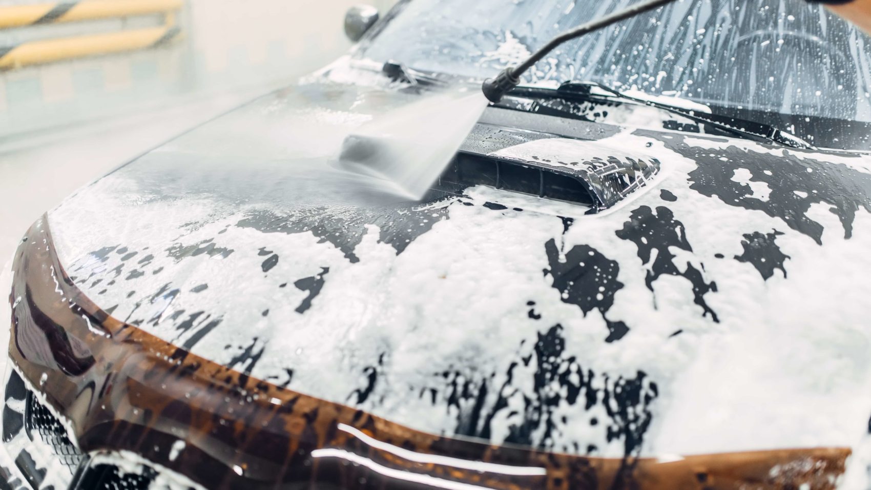 Carwash service, car cleaning, top view on hood. Auto detailing, washing foam off