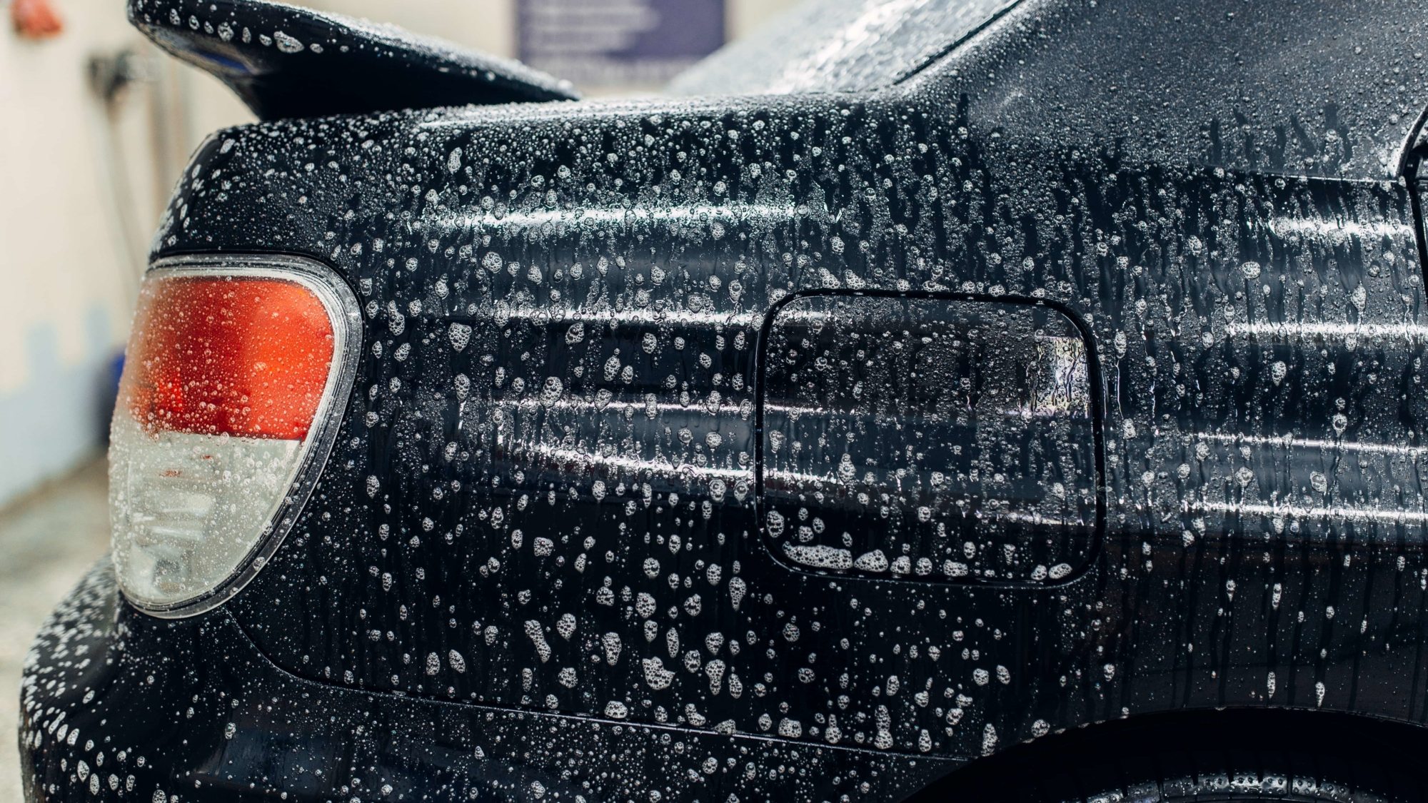 Carwash service, car in foam, side view. Auto detailing, high pressure contactless washing on special station